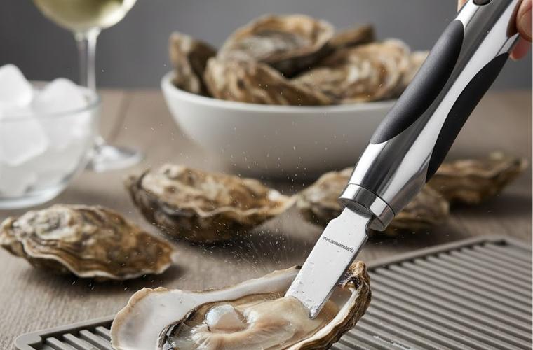 Huître ouverte posée sur une table avec un couteau électrique à huîtres